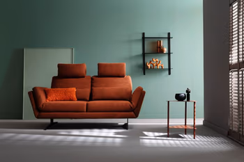 Wohnzimmer mit rotem 2-Sitzer-Sofa vor grüner Wand mit schwarzem Regal und Beistelltisch.