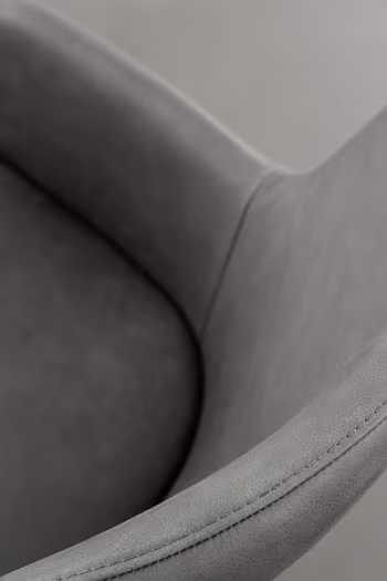 Sitzfläche und Armlehnen eines bequem gepolsterten grauen Esszimmerstuhls mit Lederbezug.