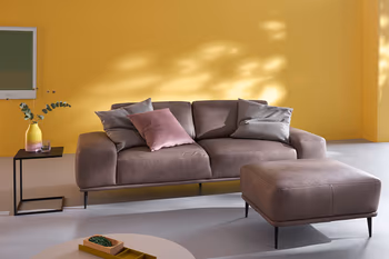 Braunes Ledersofa mit filigranen schwarzen Metallfüßen und dazu passender Hocker.