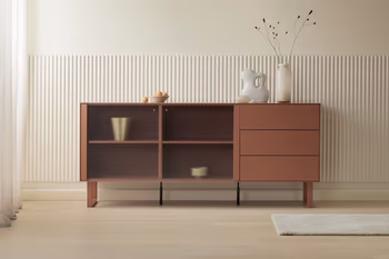 Modernes Sideboard in der Farbe Ant-Red, dekoriert mit Vasen vor beiger Wand.