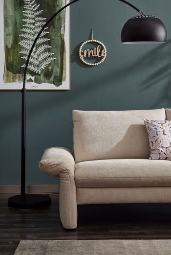 Nach außen geklappte Armlehne eines beigen Sofas.