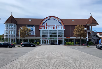 Haupteingang des Möbelhauses Wohnwelt von Harten mit einladender Glasfassade und Parkplätzen davor.