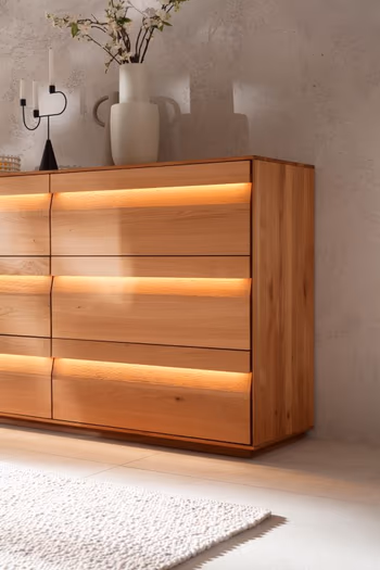 Hälfte eines Sideboards mit Schubladen, bei dem die Schubladenfronten beleuchtet sind.