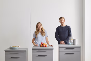 Frau und Mann stehen hinter drei ergonomisch hohen Küchenschränken.