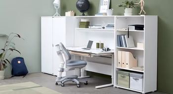 Ein Junge sitzt auf der oberen Bettes eines Etagenbetts in einem gemütlichen Innenraum mit sichtbaren Möbeln und einem Fernseher.