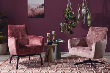 Zwei beerefarbene Sessel nebeneinander, der linke mit schwarzen Metallfüßen, der rechte mit schwarzem Drehgestell die vor einer beerefarbenen Wand stehen.