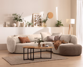 Weißes Ecksofa in organischer Form in hellem Wohnzimmer.