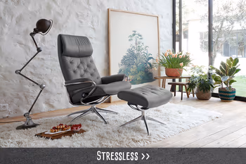 Moderner grauer Relaxsessel mit Hocker in stilvollem Wohnzimmer mit großen Fenstern und Pflanzen