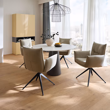 Elegantes Esszimmer mit rundem Esstisch und Armlehnstühlen in hellgrauem Leder.