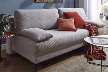 Graues Schlafsofa mit roten Kissen und roter Decke.