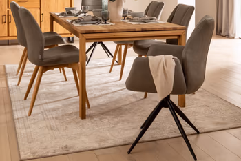 Moderne Esszimmerstühle mit und ohne Armlehne in grau, mit Holzgestell oder schwarzem Metallgestell um einen Massivholzesstisch.