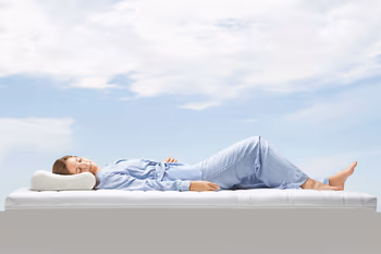 Schlafende Frau liegt auf einer Matratze unter freiem Himmer.