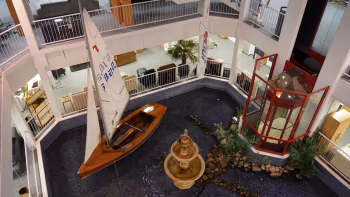 Innenansicht des Möbelhauses Wohnwelt von Harten mit einem dekorativen Biotop, einem Segelboot und einem zentralen Springbrunnen.