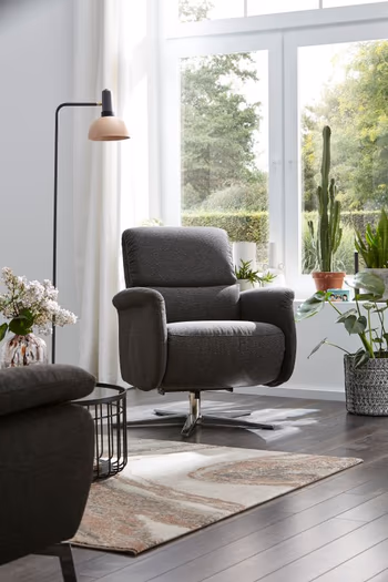 Grauer Sessel mit silbernem Sternfuß in einem hellen Raum.