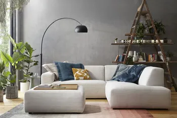 Modernes beiges Ecksofa mit Cordstoff bezogen und einem passenden Hocker, auf dem Sofa sind mehrere Kissen in blau und gelb.