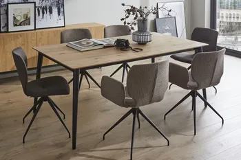 Sechs moderne Schalenstühle mit und ohne Armlehne in Grautönen und schwarzem Fußgestell um einen Holz Esstisch in einem hellen Raum.