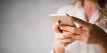 Hier gelangt man zur Terminbuchung. Auf dem Bild ist eine Frau zusehen, die auf ihr Handy tippt.