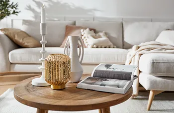 Dekorierter Runder Beistelltisch, dahinter beige Couch