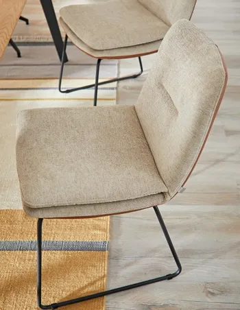 Beiger Esszimmerstuhl mit schwarzem Gestell.