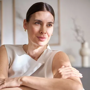 Frau sitzt auf einem Sofa und blickt entspannt in die Ferne.