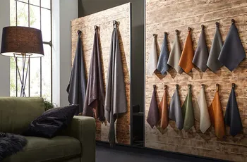 Raum mit aufgestellten Holzwänden, an denen Muster von unterschiedlichen Ledern hängen.