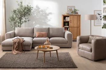 Graues Ecksofa in einem gemütlichen Wohnzimmer mit einem runden Couchtisch aus Holz und einem modernen Sessel aus grauem Leder.