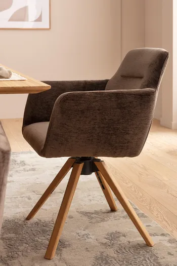 Brauner Armlehnstuhl mit Holzgestell an einem Esstisch.