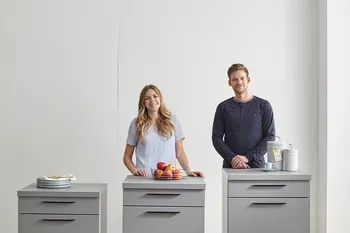 Frau und Mann stehen hinter drei ergonomisch hohen Küchenschränken.