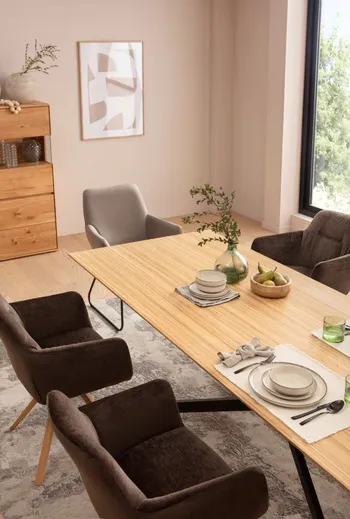 Schalenstühle in Hellgrau und Dunkelgrau an einem Hellen Holzesstisch.