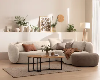 Weißes Ecksofa in organischer Form in hellem Wohnzimmer.