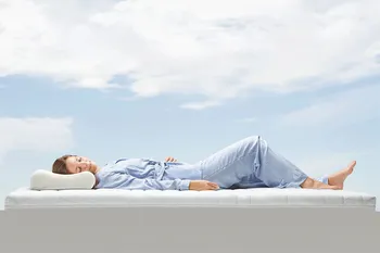 Schlafende Frau liegt auf einer Matratze unter freiem Himmer.