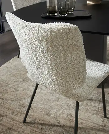 Detailbild von Rückenlehne eines modernen Esszimmerstuhls in weißem Bouclé-Stoff.