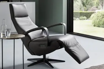 Relaxsessel mit offenen Armlehnen und leicht nach oben geklappter Fußlehne mit braunem Lederbezug.