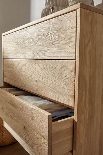 Seitenansicht einer Kommode aus hellem Holz.