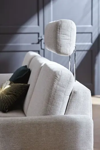 Seitenaufnahme eines grauen Sofas, mit einer hochgestellten Kopfstütze.