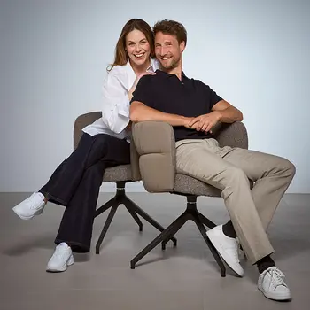 Lächelndes Paar sitzt auf modernen, gepolsterten Drehstühlen mit Armlehnen – ergonomisches Design für stilvolles und komfortables Sitzen im Essbereich.