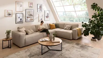 Helles Wohnzimmer mit beigem Ecksofa und rundem Couchtisch.