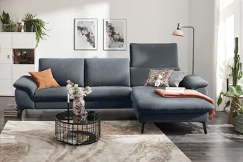 Graues Ecksofa mit erhöhter Rückenlehne bei Longchair in eine gemütlichen Wohnzimmer.