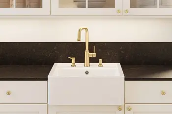 Weißer Spülstein mit goldener Armatur.