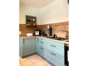 Eckküche mit grüner Front und Arbeitsplatte aus Holz