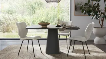 Helles, modernes Esszimmer mit schwarzem Esstisch und Esszimmerstühlen in weißem Stoff.