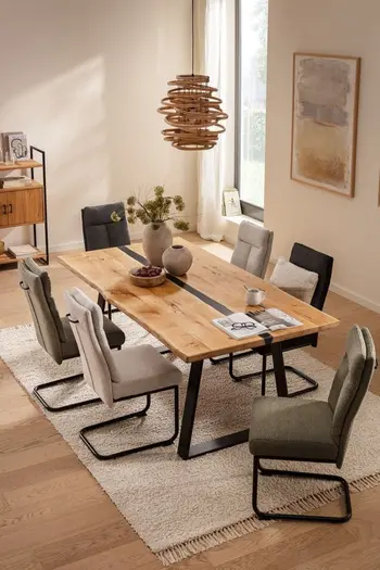 Modernes Esszimmer mit mehreren Freischwinger Esszimmerstühlen in beige, grau und grün an einem großen Esstisch aus Massivholz.