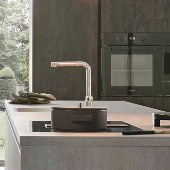 Moderne graue Küche mit Kücheninsel und großem Schrank mit Backofen im Hintergrund