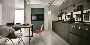 Graubraune Winkelkueche mit Einbaugeraeten und gruenen Akzenten.