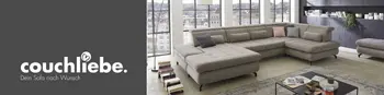 Modernes Wohnzimmer mit großer, orangefarbener Eckcouch von Couchliebe, dekoriert mit Kissen und einem schwarzen runden Couchtisch mit Trockenblumen. Im Hintergrund ein Sideboard mit minimalistischer Deko, große Fensterfront mit Blick ins Grüne.