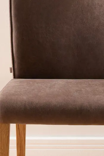 Detailbild von Sitzfläche eines Esszimmerstuhls mit Kaltschaumpolsterung und braunem Stoffbezug.