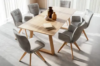 Graue Esszimmerstühle aus Leder mit und ohne Armlehne um einen modernen Tisch aus Massivholz in einem hellen Esszimmer. 