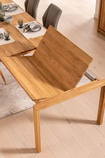 Heller Massivholzesstisch, bei dem gerade die Tischplatte erweitert wird für mehr Platz.
