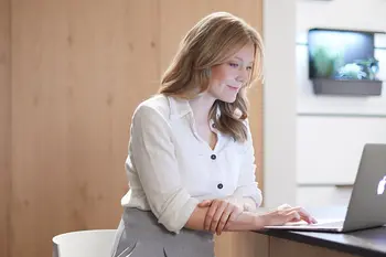 Frau sitzt in der Küche am Laptop und arbeitet.