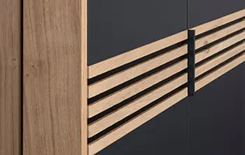 Detailansicht eines modernen Kleiderschranks mit mattschwarzen Fronten und dekorativen, horizontalen Holzleisten – stilvolle Kombination aus Holz und Schwarz für ein elegantes Schlafzimmerdesign.